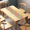 A light wood dining table set with a colorful Day of the Dead linen table runner.