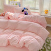 A pink solid cotton bed linen set with a duvet and pillows is displayed on a bed.