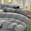 A gray solid cotton bed linen set with a duvet and pillows is displayed on a bed.