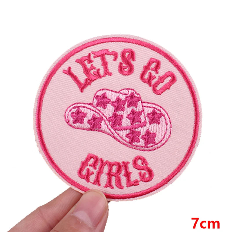 Pink embroidered patch with the text Let's Go Girls on a pink background