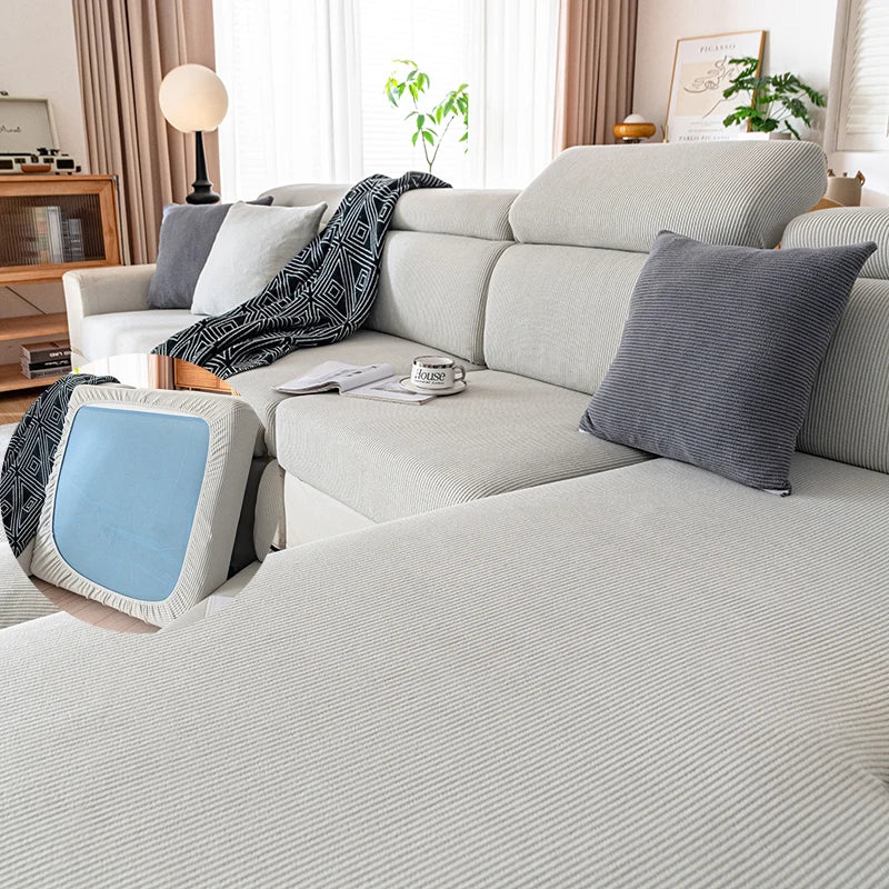 A light gray plush elastic sofa cushion cover with dark patterned fabric and a blue accent cushion.