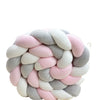 A handmade knotted floor mat for bed decor made of soft pink and gray yarn.