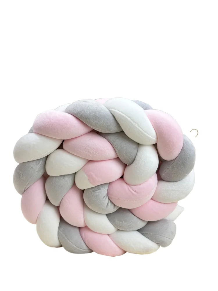 A handmade knotted floor mat for bed decor made of soft pink and gray yarn.