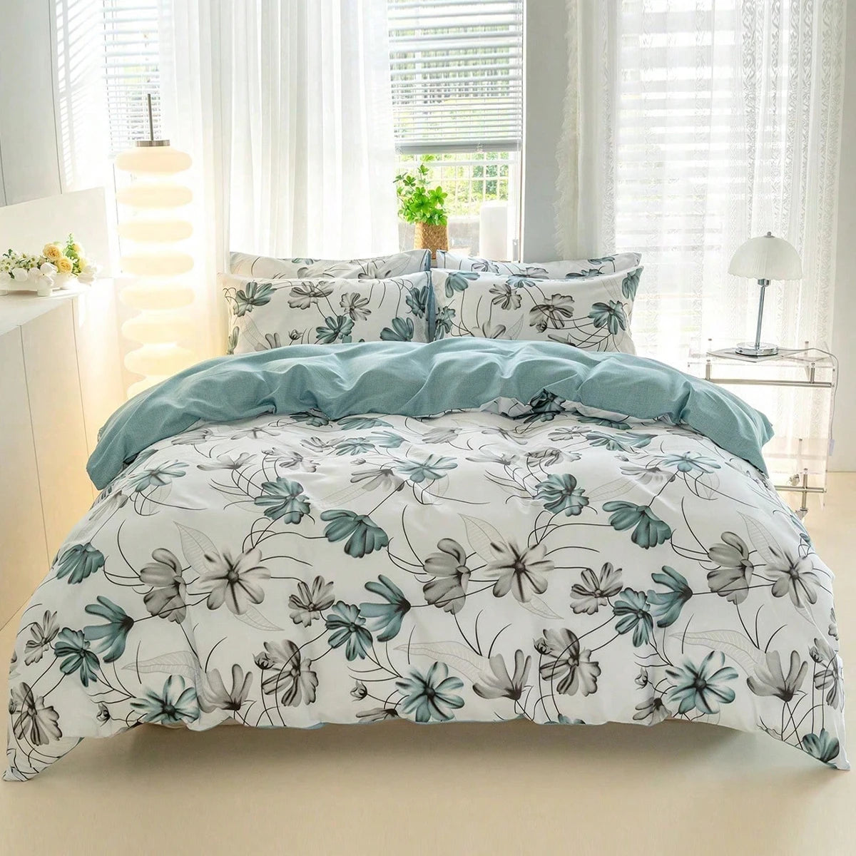 A white duvet cover with a watercolor floral pattern in teal and grey is displayed on a bed.