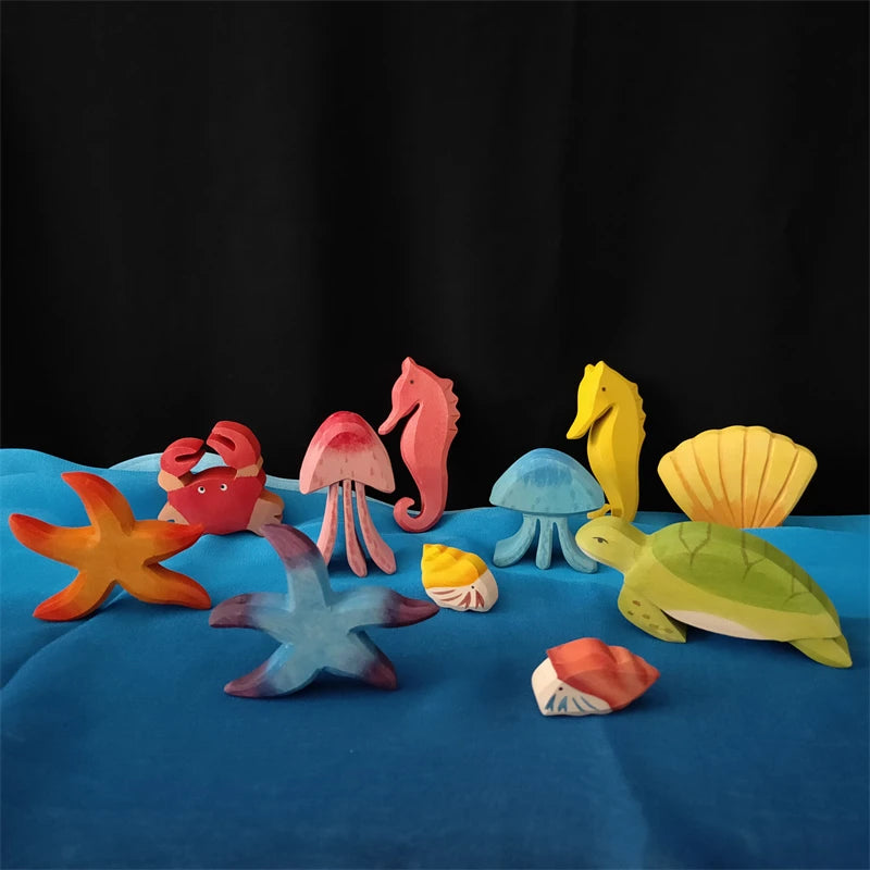 A collection of colorful, natural-looking play scarves shaped like sea creatures and mushrooms on a blue fabric.