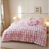 A pink and white checkered plush rabbit quilt comforter displayed on a bed with light wood accents.