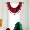 A deep red velvet window curtain valance with tassels hanging over a white window.