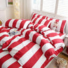 A set of three red and white striped duvet covers arranged on a bed.