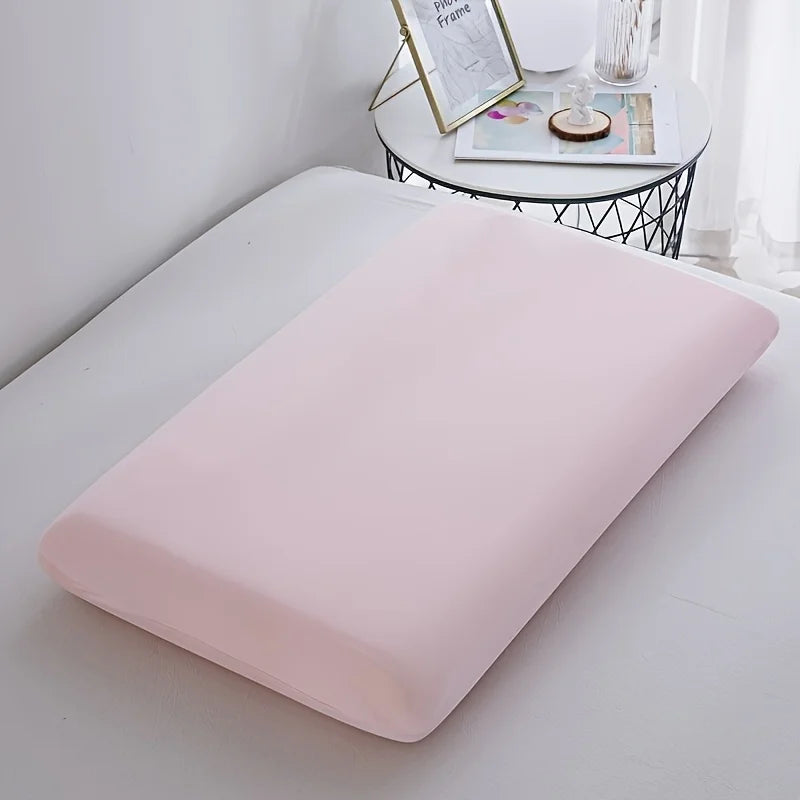 A pink ice silk cooling pillowcase resting on a white surface next to decorative items.