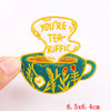 An embroidered patch featuring the text YOU'RE TEA-RIFFIC on a teal mug design.
