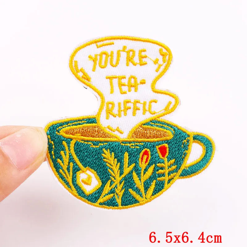 An embroidered patch featuring the text YOU'RE TEA-RIFFIC on a teal mug design.