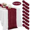 Burgundy cheesecloth table runner draped on a white tablecloth with pink flowers and gold accents.