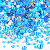 A pile of assorted blue and clear glass rhinestones for DIY crafts