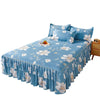 A blue floral printed bed skirt with ruffled layers and white flower accents on a bed.