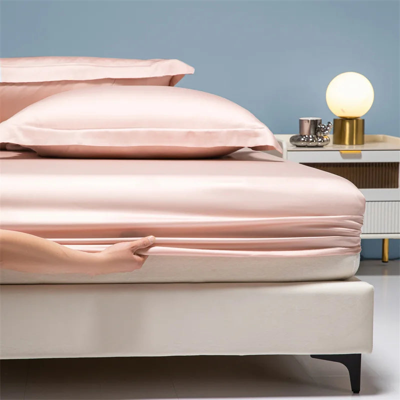 A close-up of a pink luxury bamboo bedding set on a bed with a light blue wall and bedside table.