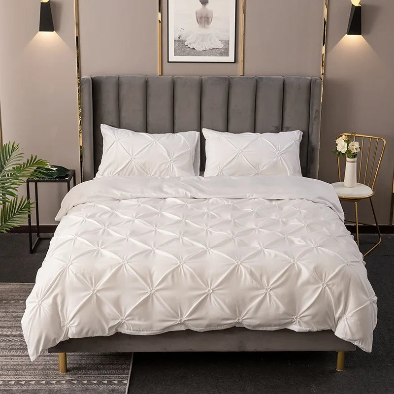 White quilted bedding set with a gray upholstered headboard and gold accents in a bedroom setting.