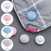 Various colored fabric clips and a white clip are shown against a gray plaid fabric background.