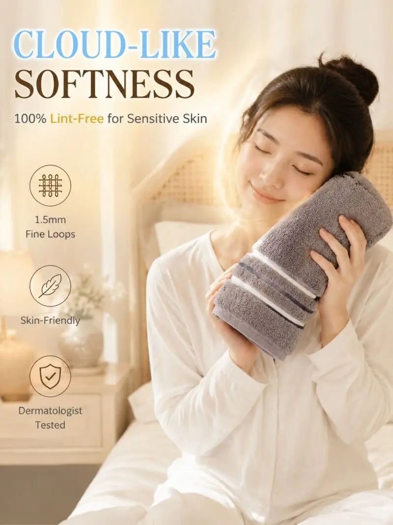 A woman is gently using a gray, soft towel on her face in a bright, indoor setting.