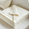 A stack of white breathable waffle quilt blankets folded neatly on a bed.