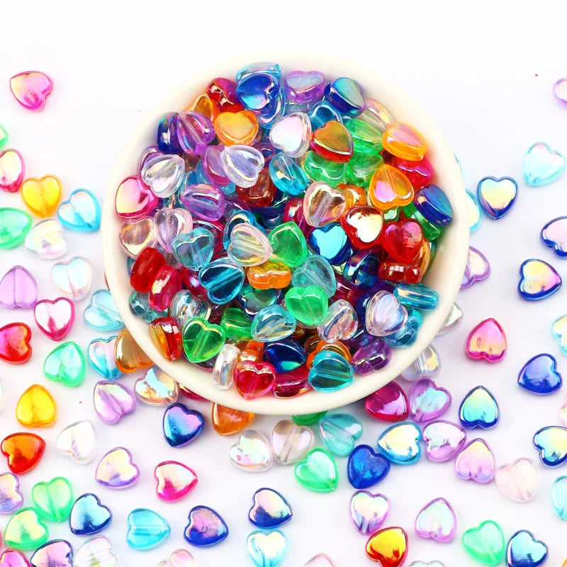 A bowl filled with colorful acrylic heart beads in various shades of pink, blue, green, and yellow for jewelry making