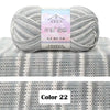 A ball of light gray yarn labeled as 4-Ply Cotton Knit Yarn for Gradient Projects resting on a gray knitted fabric background