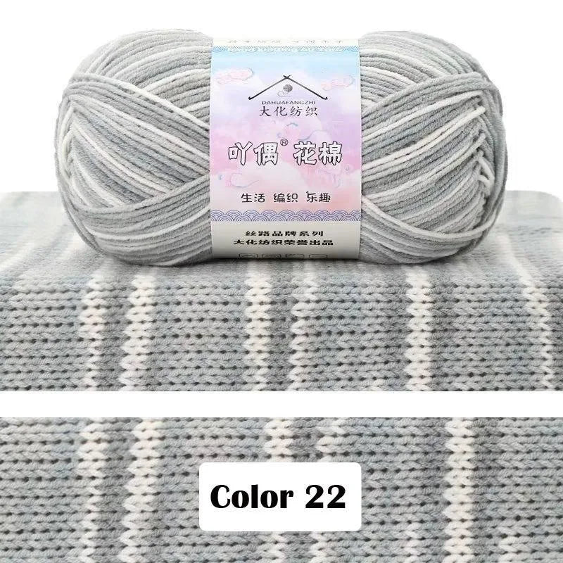 A ball of light gray yarn labeled as 4-Ply Cotton Knit Yarn for Gradient Projects resting on a gray knitted fabric background