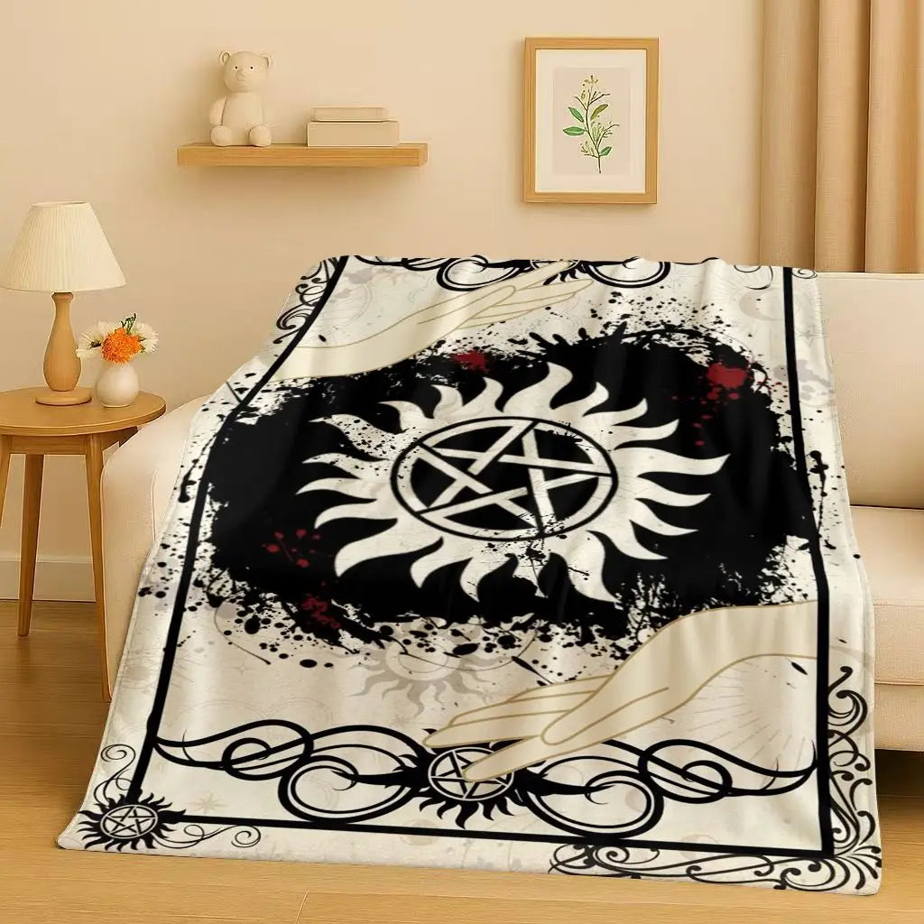 A black and white graphic flannel throw blanket featuring a sun design and decorative scrollwork.