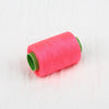 A roll of bright pink handmade sewing thread with a green core.