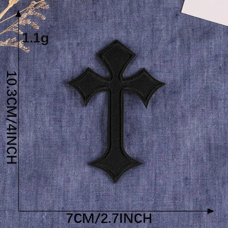 A black cross embroidery patch on a blue denim fabric background.