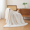 A fluffy white flannel throw blanket draped on a wooden chair next to a desk.
