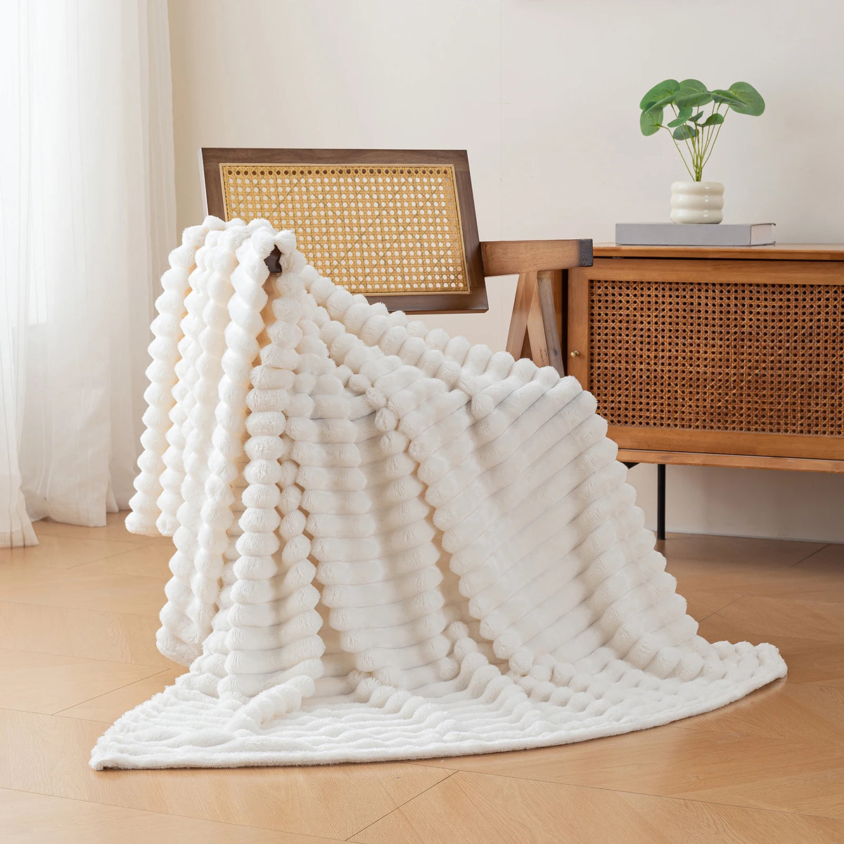 A fluffy white flannel throw blanket draped on a wooden chair next to a desk.