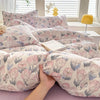 A close-up of a pink and blue floral print duvet cover featuring cute dog motifs on a bed.
