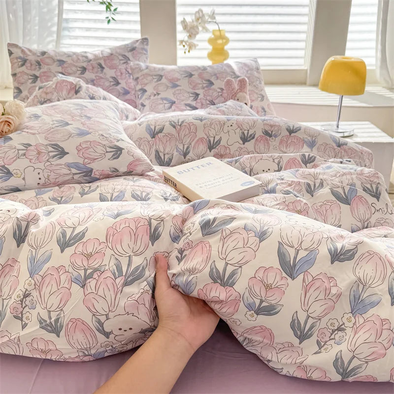 A close-up of a pink and blue floral print duvet cover featuring cute dog motifs on a bed.
