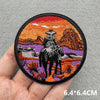 An embroidered patch featuring a silhouette of a cowboy riding a horse against an orange and purple sunset background.