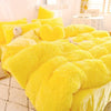 A bright yellow plush mink velvet duvet set with fluffy pillows on a bed.