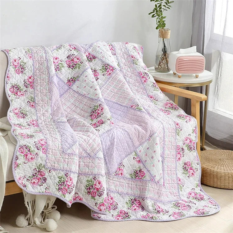 A pink and white patchwork floral plaid cotton quilt draped on a wooden surface.