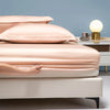 A close-up of a luxury bamboo bedding set featuring soft pink and beige sheets on a bed.