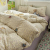A floral patterned duvet set with a light beige background is displayed on a bed, featuring a stuffed animal pillow.