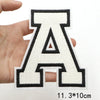 A letter patch shaped like the letter A in black and white embroidery held by a hand.