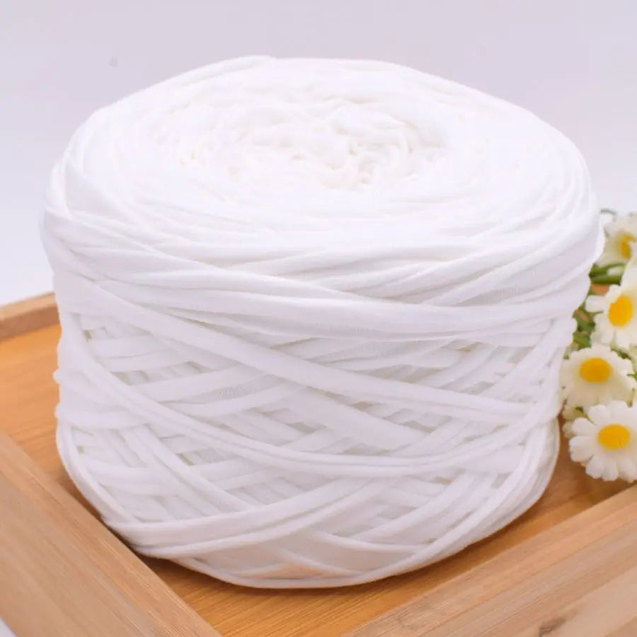 A ball of white polyester craft yarn for knitting and DIY displayed on a wooden board.