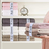 A hand holds a stack of four folded towels secured with elastic straps, labeled Full Twin, Full King, and Full Queen.