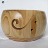 A light-colored wooden yarn bowl with a curved, organic shape and a spiral cutout for organization.