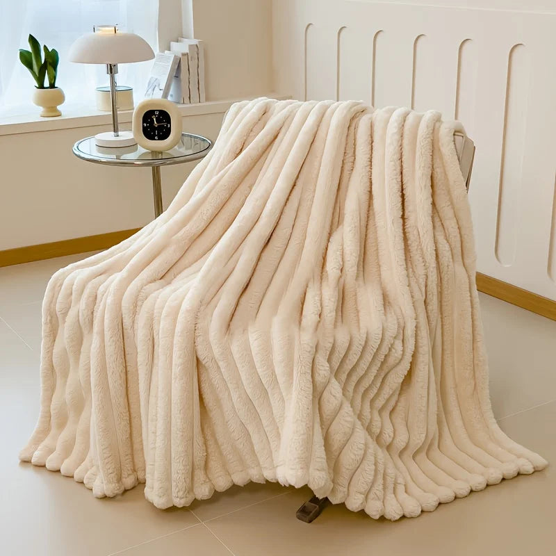 A thick, cream-colored fluffy blanket draped on a floor, showing its soft texture and drape.