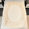 A round, cream-colored knitted item resembling a wreath or oval frame, likely a decorative textile.