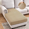 A beige jacquard stretch sofa cushion cover placed on a light gray sofa, shown with an inset detail of the fabric pattern.