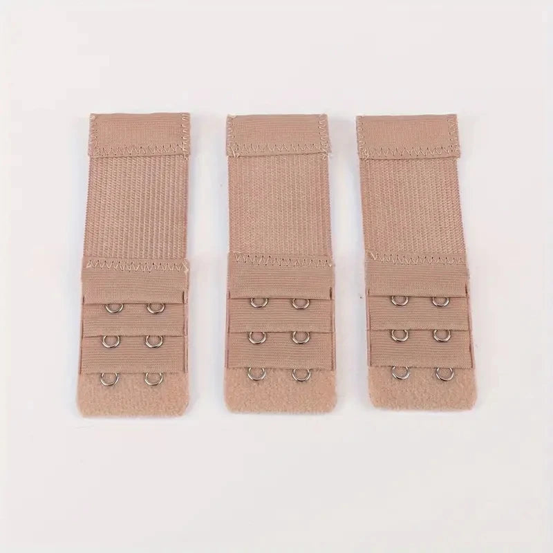 Three beige adjustable bra extender straps laid out side by side.