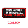 Black embroidered patch with red text that reads What Happens In The Garage Stays In The Garage