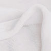 A close-up of a white vintage floral patchwork throw blanket draped softly.