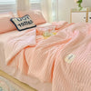 A pink Korean style seersucker summer quilt set displayed on a bed with white and pink accents.