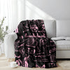 A pink retro punk print blanket draped over a white sofa with bright sunlight streaming in.